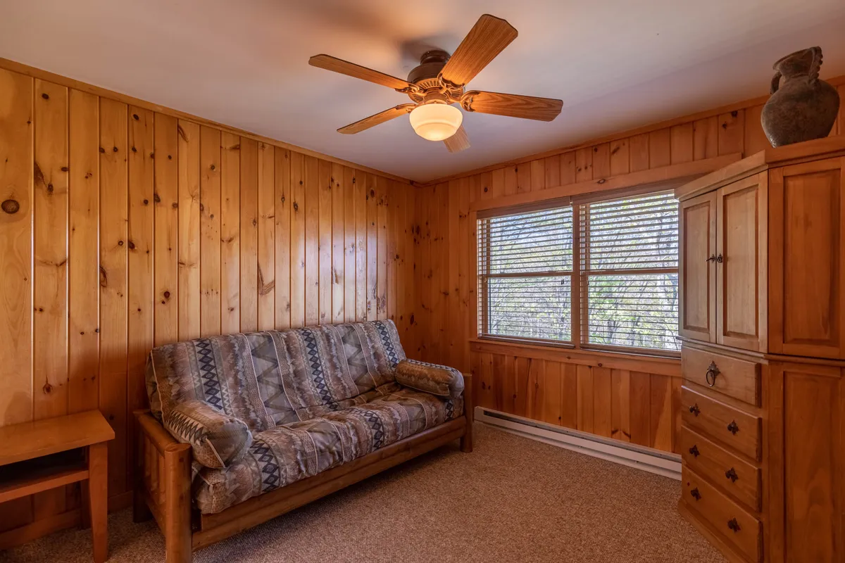 A cozy sofa and sturdy wooden furniture are arranged in a bright, inviting room with a large window. The setting is ideal for quiet relaxation, reading, or enjoying sunset views after an active day exploring the area.